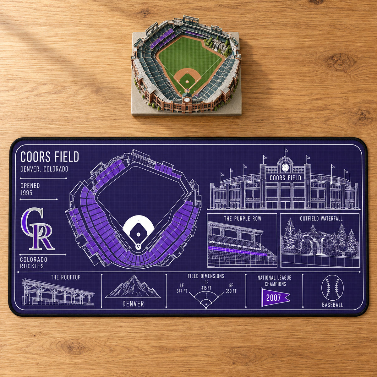 Colorado Rockies Coors Field blueprint desk mat, 16" x 32", on a wooden desk with a decorative stadium model